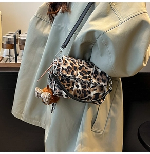 Detail of leopard print crossbody bag with silver chain and cute plush bear charm