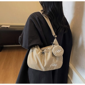 Dettaglio borsa a tracolla in tela beige con chiusura a coulisse e mini pochette