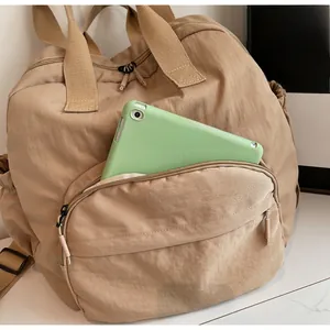 Close-up of the front zipper pocket on a khaki tote bag holding a green tablet device