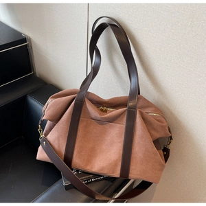 Detail view of large caramel tote bag featuring deep brown leather handles and side buckles
