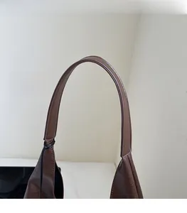 Detail of wide brown leather shoulder strap with sturdy stitching and lychee grain texture