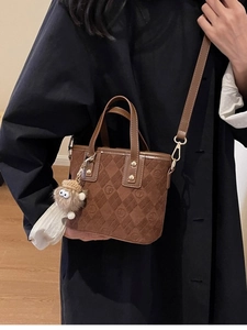 Brown frosted retro bucket bag with monogram embossing and plush keychain on a model