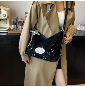 Detail of glossy black shoulder bag with silver hardware and a star-shaped charm accessory