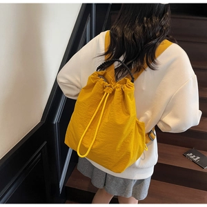 Vista posteriore di uno zaino in nylon giallo con coulisse indossato da una modella