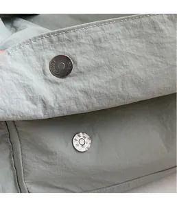 Detail of metal magnetic buckle on grey nylon tote bag showing secure closure