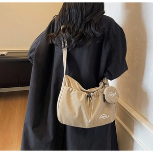 Dettaglio borsa a tracolla in nylon beige con chiusura a coulisse e piccolo portamonete