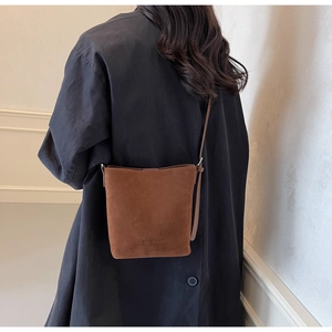 Rear view of model wearing a vintage brown suede bucket bag with crossbody strap