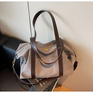 Detail of grey canvas tote bag with brown leather straps on a sofa in a lifestyle setting