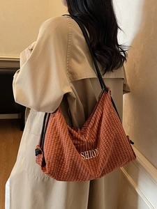 Plaid canvas shoulder bag with SHION embroidery and rope strap on beige coat background