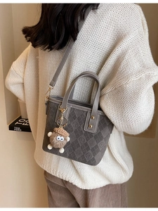 Quilted gray faux suede bucket bag with crossbody strap and plush monster charm