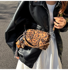 Detail of leopard print crossbody bag with woven texture and cute bear charm pendant