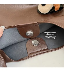 Detail view of the magnetic closure and brown lychee grain leather on a tote bag