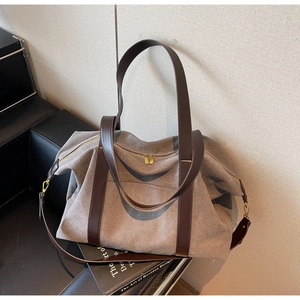 Detail of grey canvas tote bag with leather handles and gold hardware on a chair