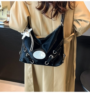 Close-up of black patent leather hobo bag with silver star charm and metallic buckles
