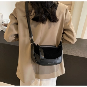 Detail view of the black moon-shaped shoulder bag featuring fashion branding and metal buckle