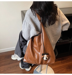 Close-up of caramel brown pebble leather tote bag with cute plush dog charm detail