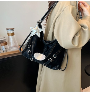 Detail of black glossy patent leather shoulder bag with Y2K star charm and silver hardware