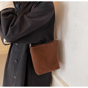Detailed view of the dark brown matte shoulder bucket bag with fine strap on model