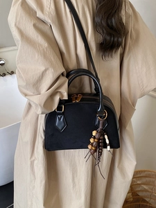Elegant black suede pillow bag with golden hardware and colorful wooden bead tassel charm