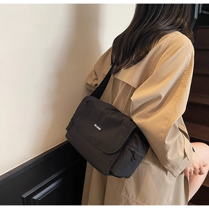 Detail of black nylon messenger bag with flap and YOU & BEAR logo on casual model