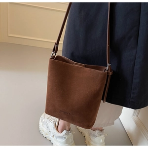 Detail of coffee brown matte bucket bag with adjustable strap and embossed text