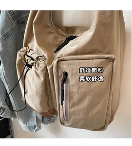 Dettaglio della borsa a tracolla in nylon kaki con chiusura a coulisse e tasca con zip