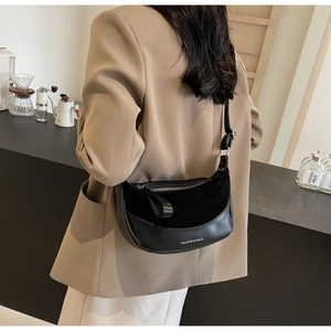 Detail of a black crescent shoulder bag featuring mixed leather and suede textures