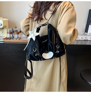 Detail of glossy black patent leather tote bag with silver star charm and metal rings