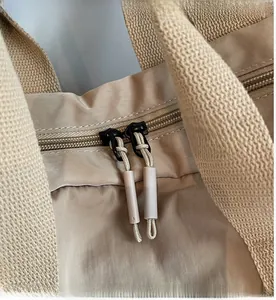 Detail of smooth double zipper with cord pulls on a beige waterproof nylon travel backpack
