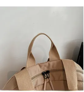 Close-up of woven handle and double zipper details on a beige nylon travel backpack