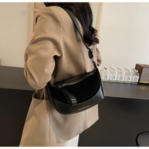 Detail view of a black crescent saddle bag with leather texture shown on a model