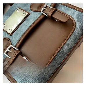 Close-up of vintage denim shoulder bag with brown leather trim and silver metal buckle