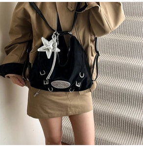 Detail of black nylon shoulder bag with silver star pendant and metallic accents