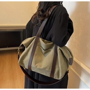 Detail view of large olive canvas tote bag with brown leather straps on a wool coat