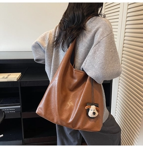 Detailed close-up of brown PU leather tote bag with a cute plush dog charm