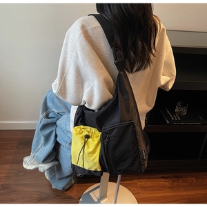 Dettaglio della borsa a tracolla con tasca gialla a coulisse e materiale in nylon resistente