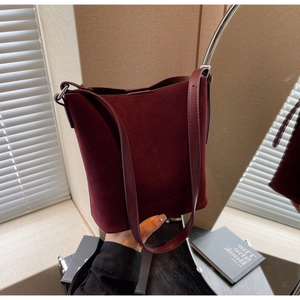 Detail view of burgundy bucket bag featuring suede leather texture and brand lettering