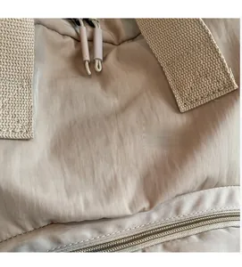 Detail of high-quality beige nylon fabric texture and durable reinforced strap on tote bag