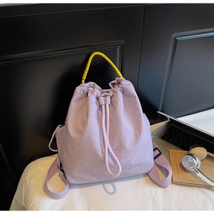Dettaglio borsa a secchiello in nylon lilla con manico intrecciato giallo vivace