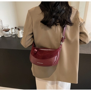 Detail of burgundy crescent saddle bag in mixed leather and suede worn by a model