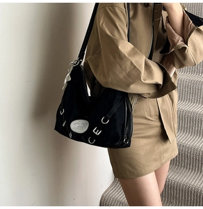 Detail of black suede tote bag with silver metal rings and cute white cat pendant