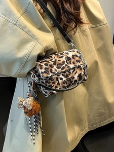 Stylish leopard print crossbody bag with silver chain and cute puppy charm on a model