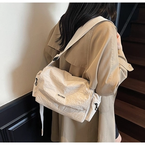 Detail of cream oversized messenger bag with natural crinkled texture and wide shoulder strap