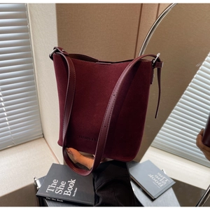 Detail of burgundy matte leather bucket bag with embossed text and slim strap