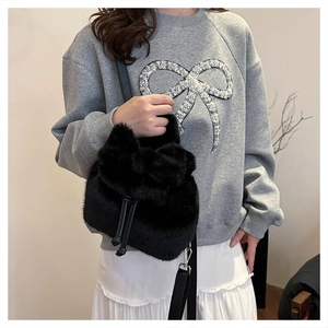 Detail van zwarte faux fur emmertas met trekkoordsluiting en leren schouderband