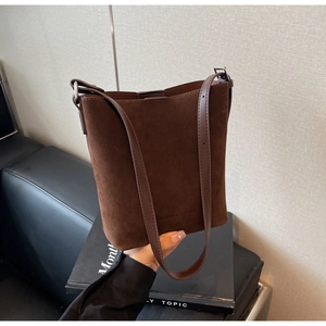 Detail of dark brown matte bucket bag with embossed lettering and adjustable shoulder strap