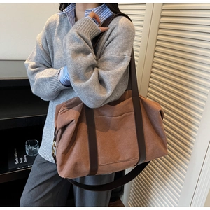 Detail of caramel canvas tote bag with brown leather handle and gold metal hardware
