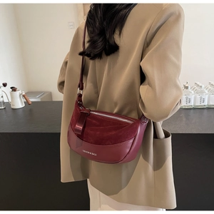 Detailed back view of dark burgundy half-moon saddle bag with suede stitching and strap