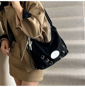 Detail of black multi-functional tote bag with silver hardware and star charm accessory