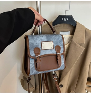 Detail of vintage denim and brown leather patchwork handbag with metallic buckle and straps